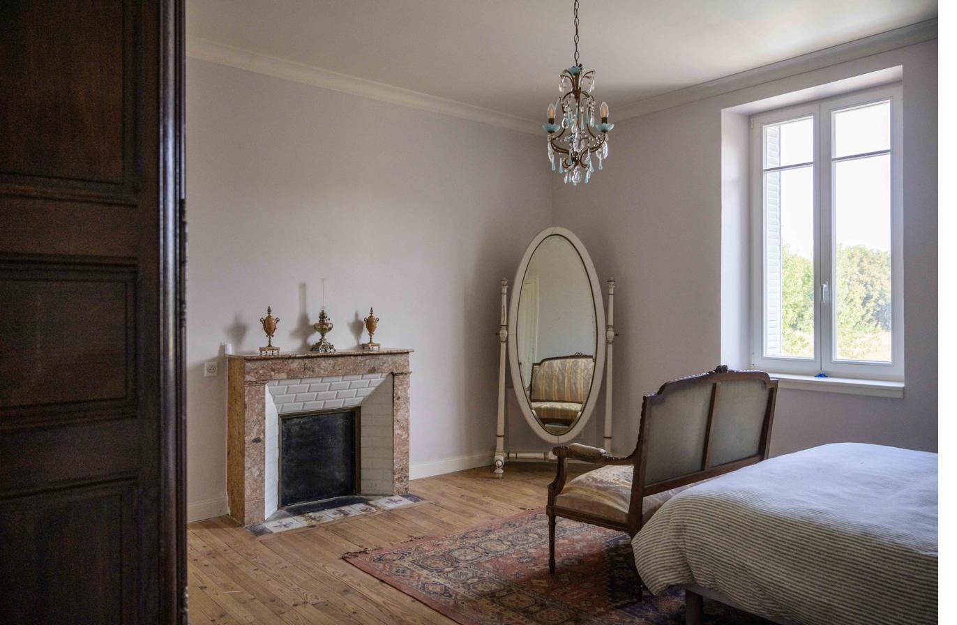 Bedroom with fireplace and cheval mirror