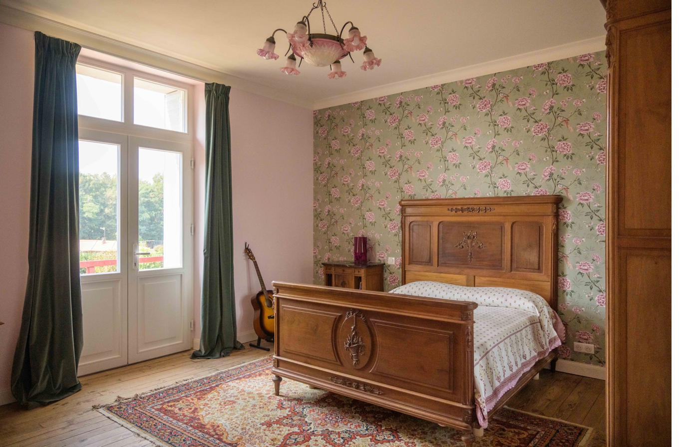 Bedroom with carved bed and rose wallpaper