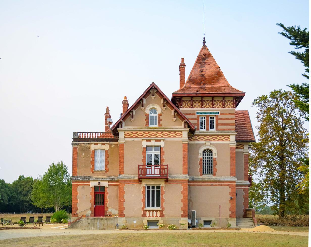 The house: red and cream brick façade with a pointed turret