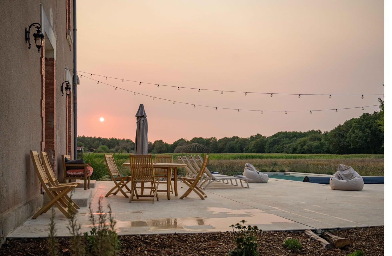 Terrace at sunset with festoon lights and the pool beyond